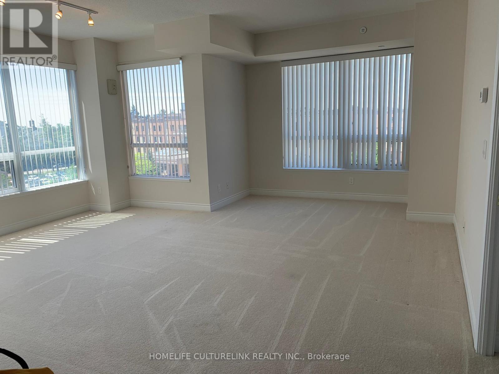 A spacious room with a carpeted floor and large windows.
