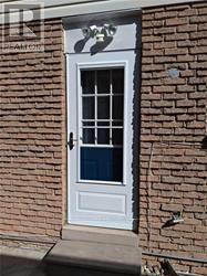 A white door with a glass window is set in a brick wall.