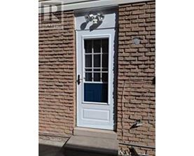 A white door with a glass window is set in a brick wall.