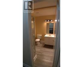 A bathroom with a toilet, sink and mirror.