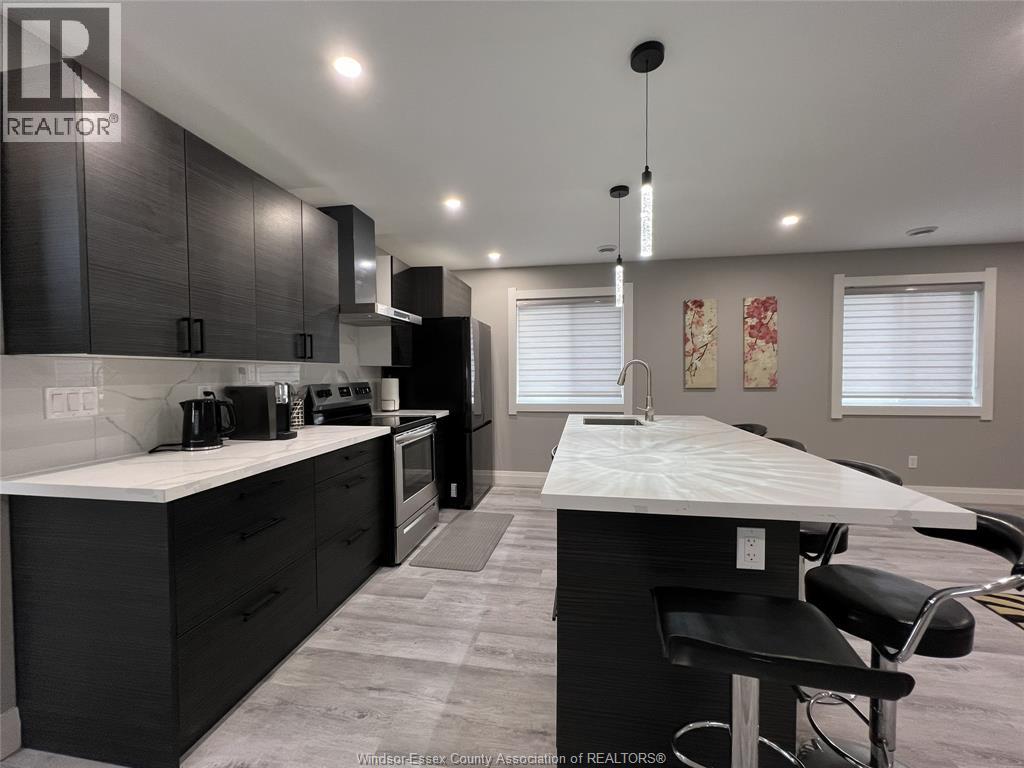A kitchen with black cabinets and a white island.