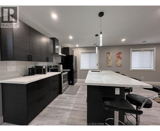 A kitchen with black cabinets and a white island.