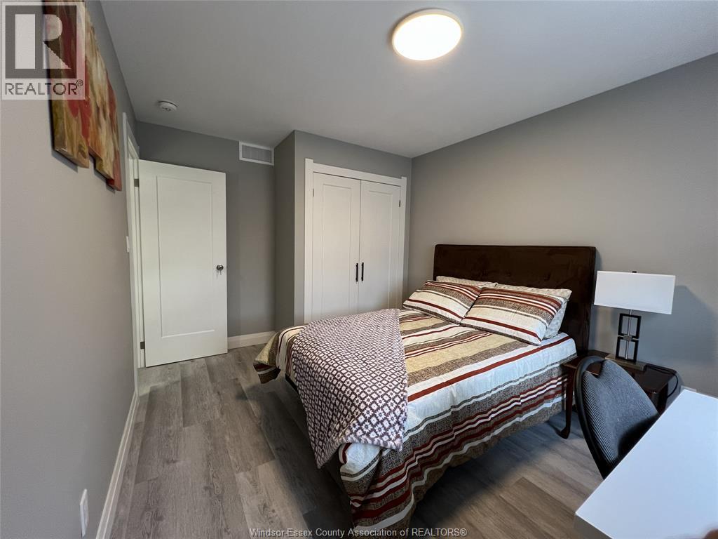 A bedroom with a bed, chair, and two doors.