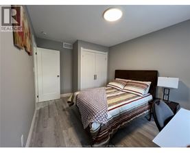 A bedroom with a bed, chair, and two doors.