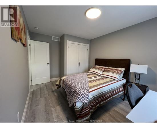 A bedroom with a bed, chair, and two doors.