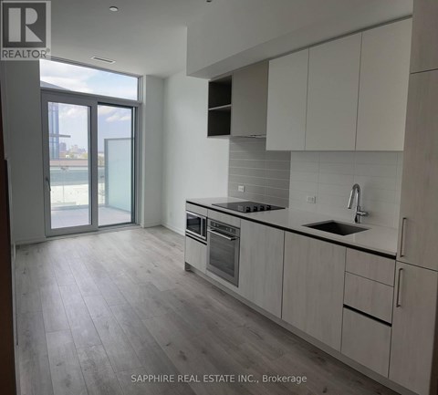 A modern kitchen with white cabinets and a large window.