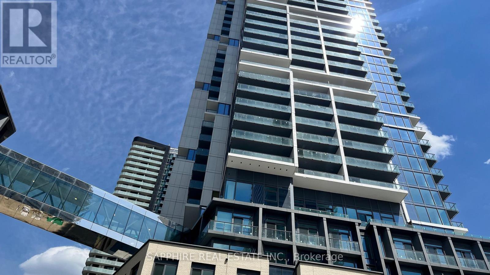 A tall building with a glass walkway on the first floor.