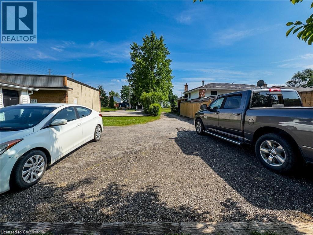 A white car is parked in a gravel lot next to a silver truck.