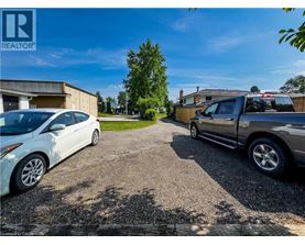 A white car is parked in a gravel lot next to a silver truck.