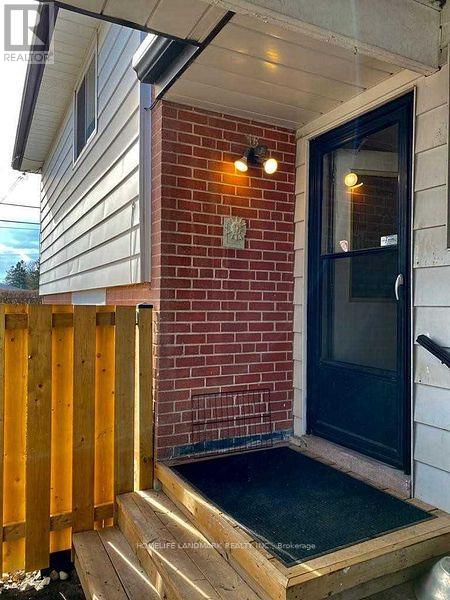 A black door with a glass window is on a brick wall.