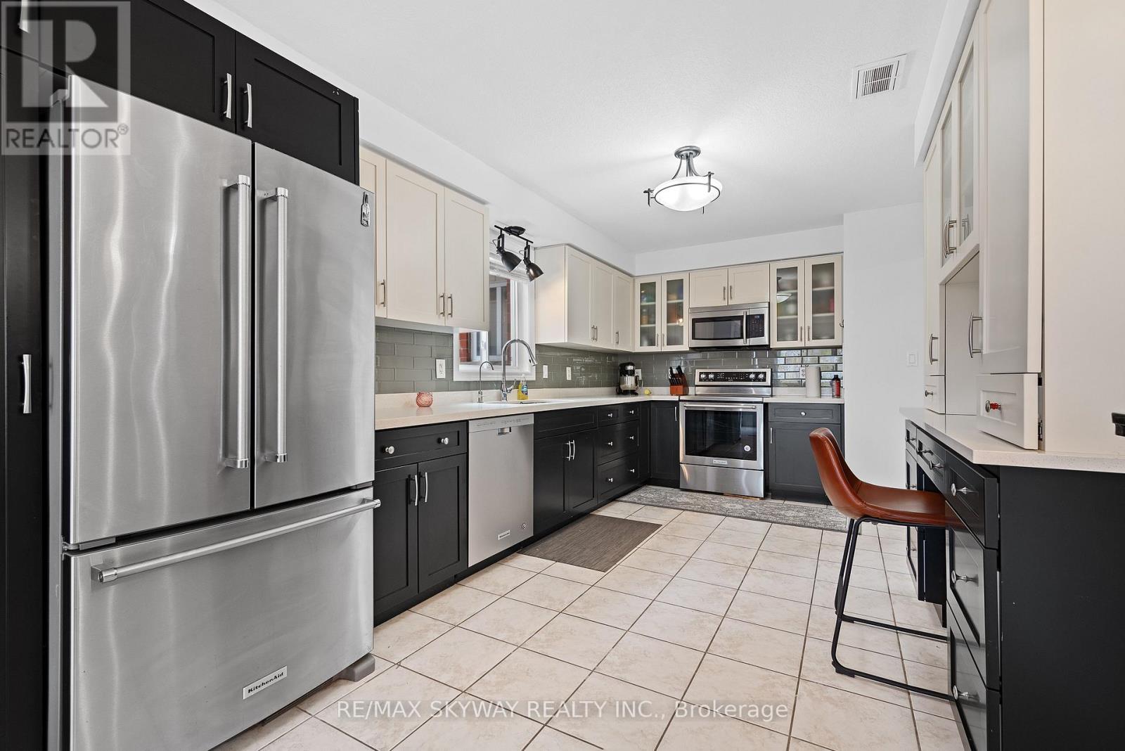 A modern kitchen with a stainless steel refrigerator and a tiled floor.