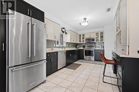 A modern kitchen with a stainless steel refrigerator and a tiled floor.