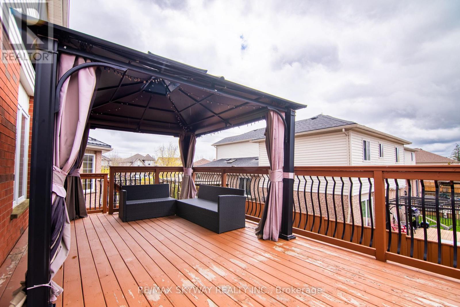 A wooden deck with a gazebo and a bench.