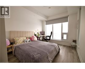 A bedroom with a large bed and a window with blinds.