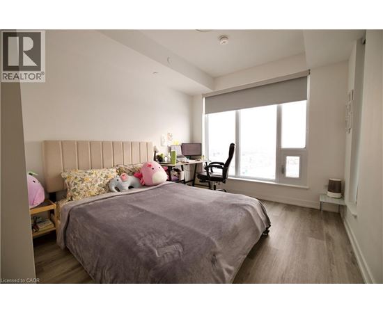 A bedroom with a large bed and a window with blinds.