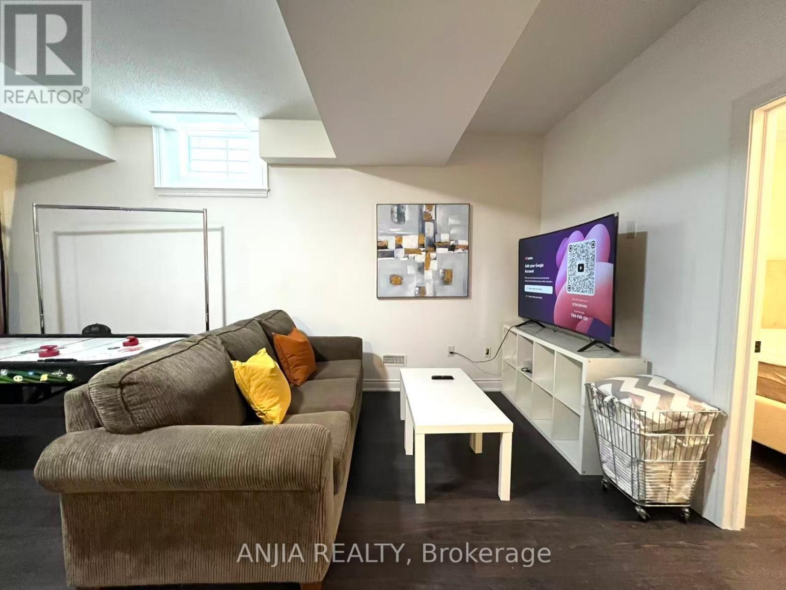 A living room with a couch, a pool table, and a television.
