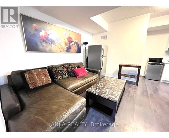 A living room with a brown leather couch and a painting on the wall.