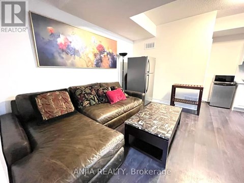 A living room with a brown leather couch and a painting on the wall.