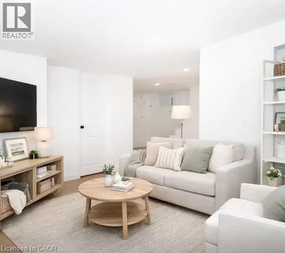 A living room with a white couch, a wooden coffee table, and a flat-screen TV mounted on the wall.