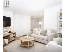 A living room with a white couch, a wooden coffee table, and a flat-screen TV mounted on the wall.