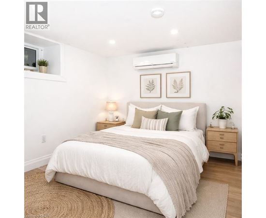 A bedroom with a large bed, a nightstand with a lamp, and two framed leaves on the wall.