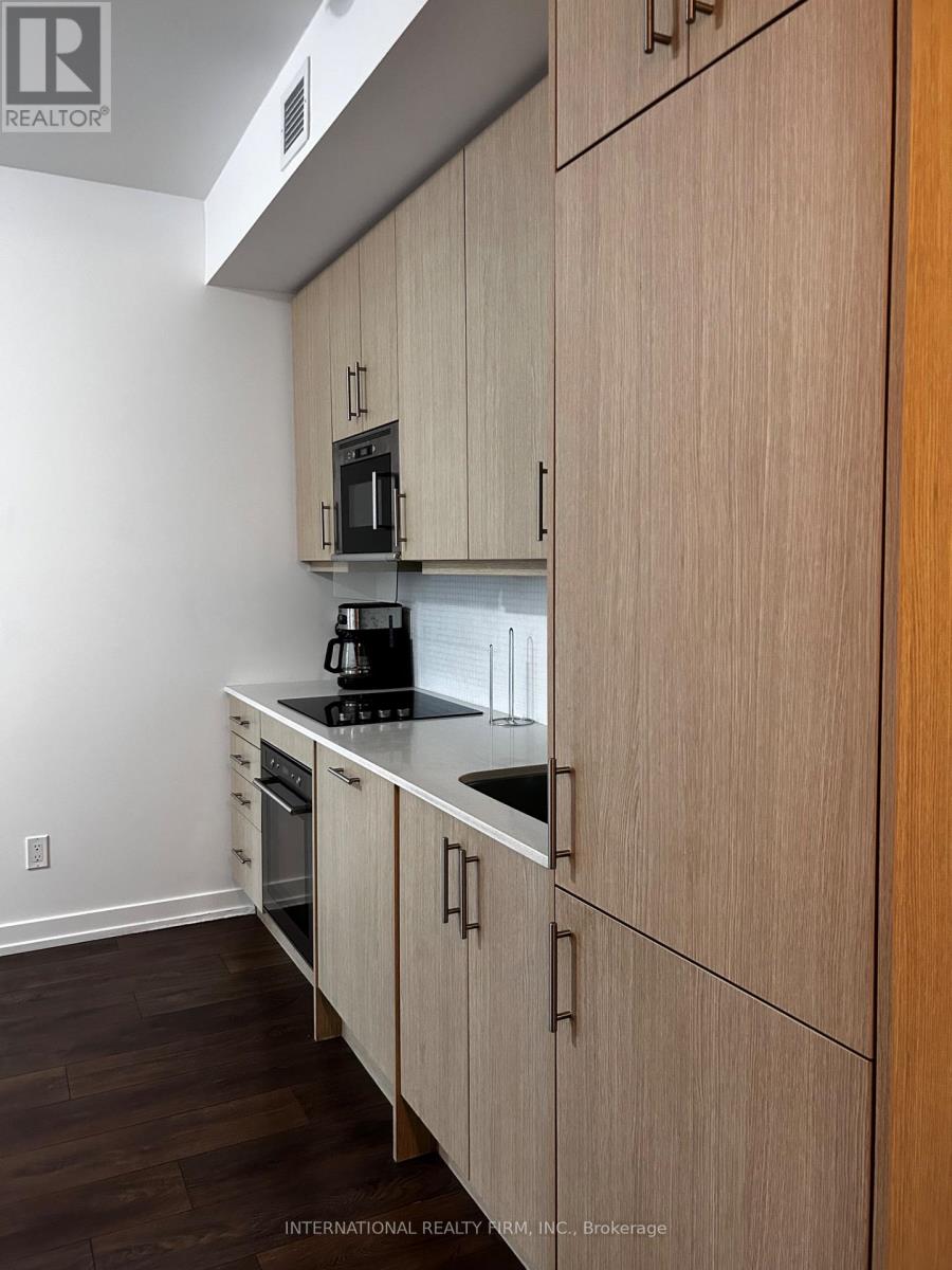 A kitchen with wooden cabinets and a black microwave.