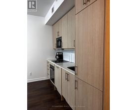 A kitchen with wooden cabinets and a black microwave.