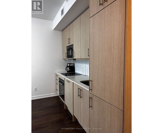 A kitchen with wooden cabinets and a black microwave.