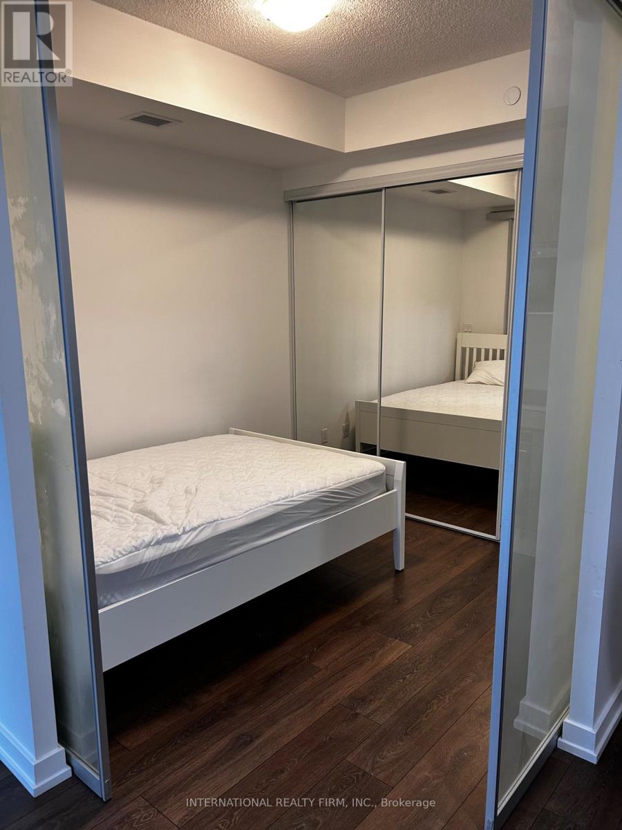 A bedroom with a bed and a mirrored closet door.
