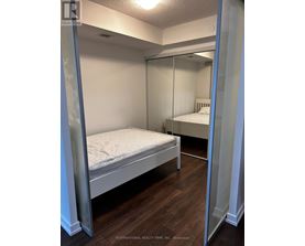 A bedroom with a bed and a mirrored closet door.