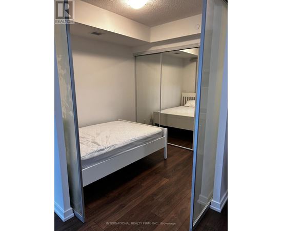 A bedroom with a bed and a mirrored closet door.