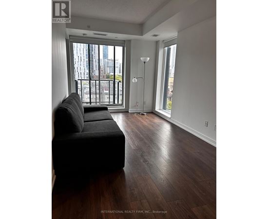 A living room with a black couch and a view of the city.