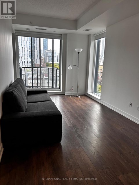 A living room with a black couch and a view of the city.