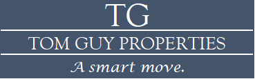 A blue sign with the letters TG and the words Tom Guy Properties and A smart move.