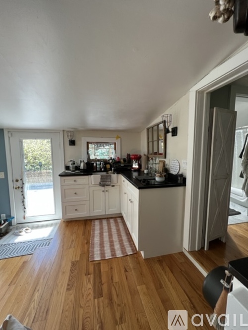 A kitchen with wooden floors and white cabinets.