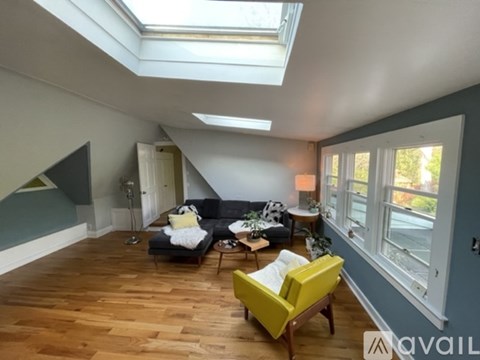 A living room with a yellow chair and a black couch.