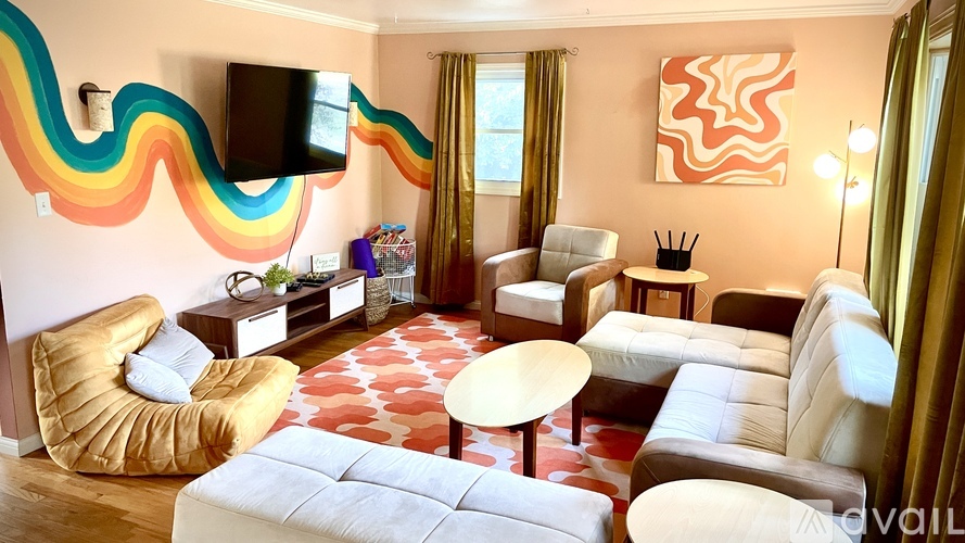 A living room with a white couch, a yellow chair, and a television mounted on the wall.