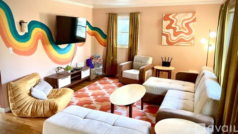 A living room with a white couch, a yellow chair, and a television mounted on the wall.