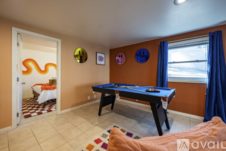 A room with a pool table and a window with blue curtains.