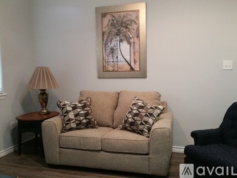 A living room with a beige couch, a lamp, and a painting on the wall.