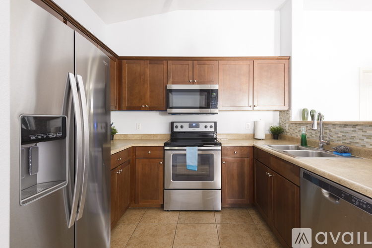 A kitchen with a stainless steel refrigerator and oven, and wooden cabinets.