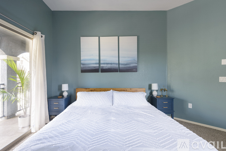 A bedroom with a large bed and a painting on the wall.