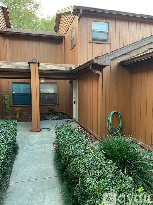 A house with a brown siding and a green hose on the wall.