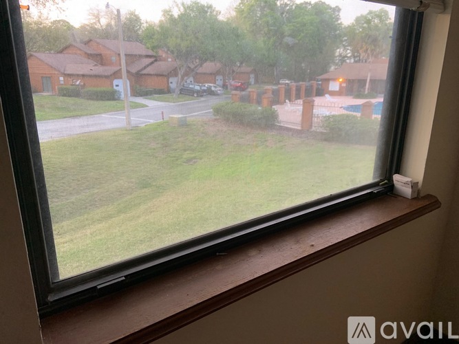A view from a window looking out to a grassy area and houses.