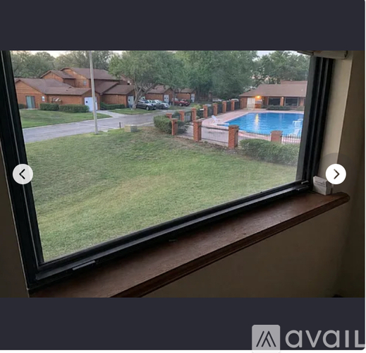 A view from a window looking out at a pool and houses.