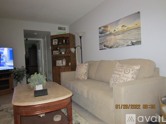 A living room with a couch, a table, and a painting on the wall.