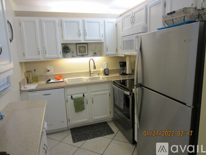 A kitchen with white cabinets and a refrigerator.