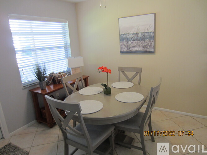 A dining room with a table set for four and a painting on the wall.