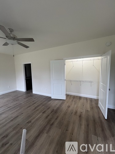 A room with a ceiling fan and wooden flooring.