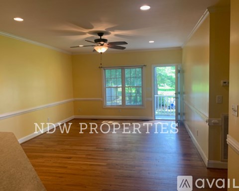 A room with a ceiling fan and a window with a view of trees.